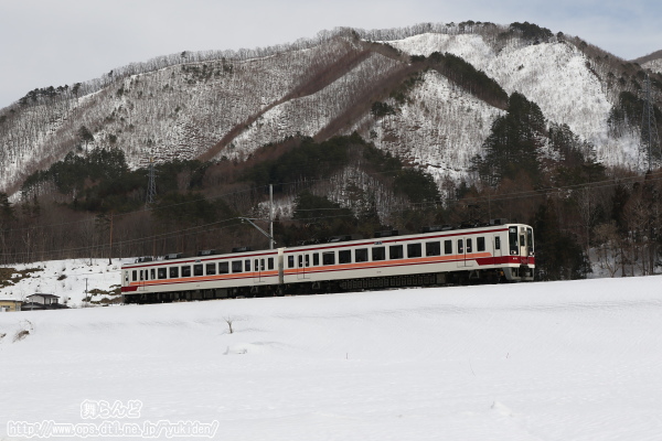 雪に覆われた築堤上を行く6176F